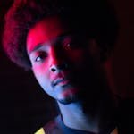 Striking portrait of a man with vibrant afro hair, captured in colorful neon lights.