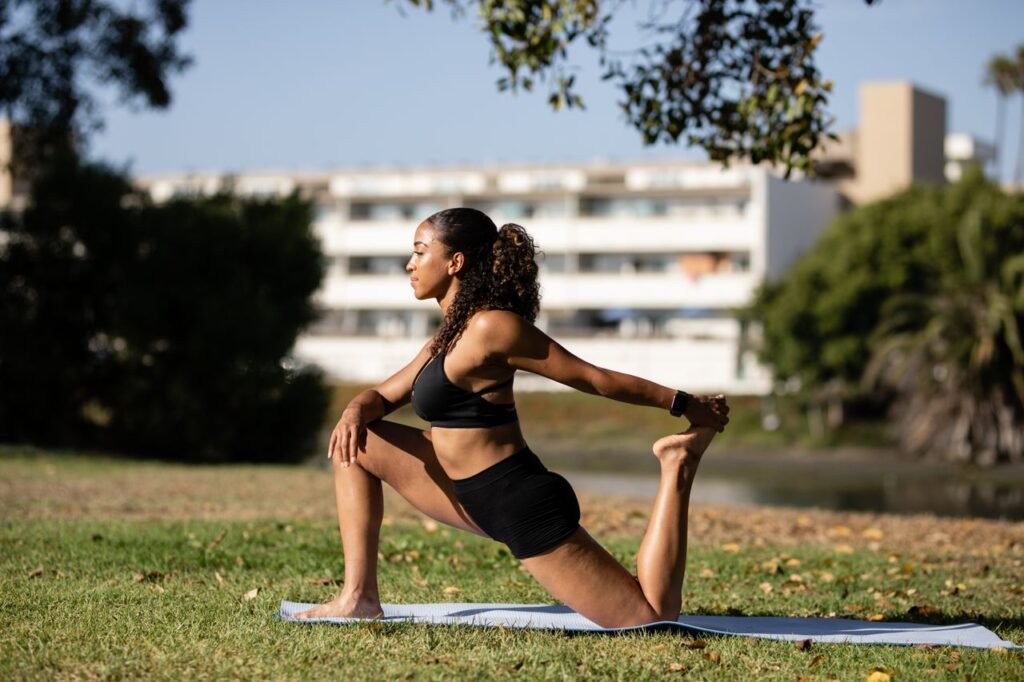 pexels-photo-4908990-4908990 African American woman stretching on a yoga mat outdoors, promoting a healthy lifestyle.